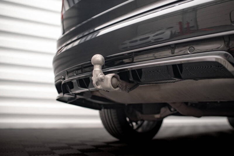 Close-up of a silver trailer hitch ball attached to a car's rear bumper, with underside components visible beneath the bumper.
