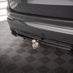 Rear view of a dark car showing a tow hitch ball attached to the bumper in a showroom setting.
