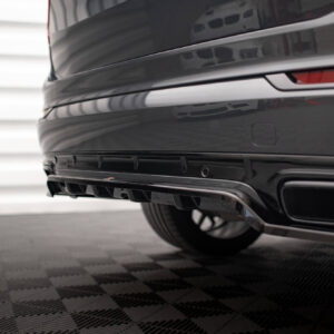 Close-up of the rear end of a glossy black car, showing the taillight strip and lower bumper on a showroom floor.