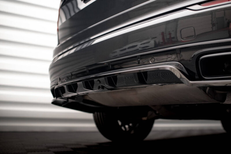 Close-up of a shiny black car rear bumper, showing the chrome trim and exhaust area in the lower rear