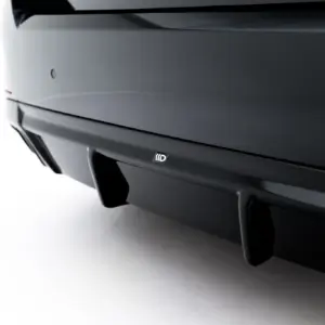 Close-up of a dark car rear bumper with a small rectangular badge visible near the center bottom of the image.