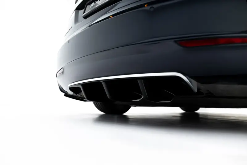 Close-up of a dark gray car's rear bumper, exhaust tips, and lower trim against a white background in a sleek, modern look.