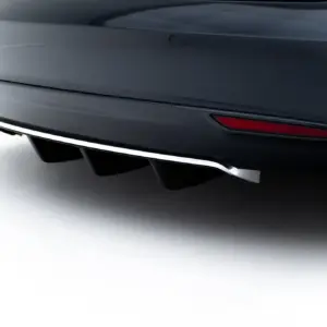 Close-up of a dark car's rear bumper showing exhaust outlets and a red reflector strip along the bumper edge.