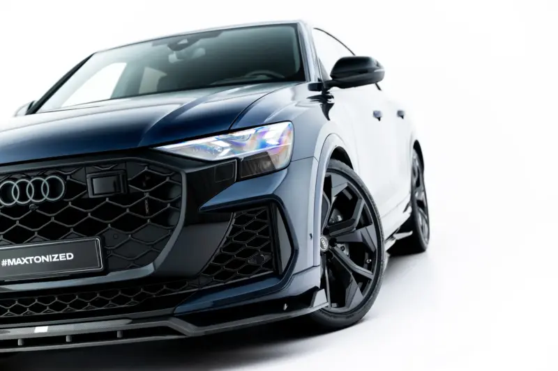 pol_po_Set-of-Prepreg-Carbon-Fiber-Splitters-Audi-RSQ8-Mk1-Facelift-23818_14webp - OPSHOLDERS Close-up of a dark blue Audi front end with honeycomb grille and sharp headlight, angled to the left (showing the logo area)