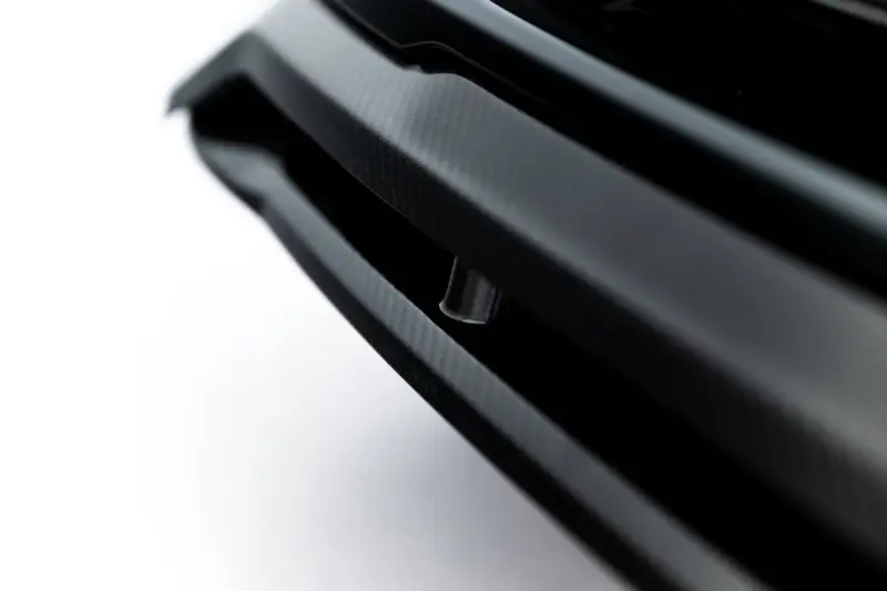 pol_po_Set-of-Prepreg-Carbon-Fiber-Splitters-Audi-RSQ8-Mk1-Facelift-23818_18webp - OPSHOLDERS Close-up of a textured carbon fiber surface with glossy black curved strips, diagonal composition, abstract industrial feel