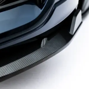 Close-up of a glossy black car wheel with a carbon fiber rim and tire against a light background.