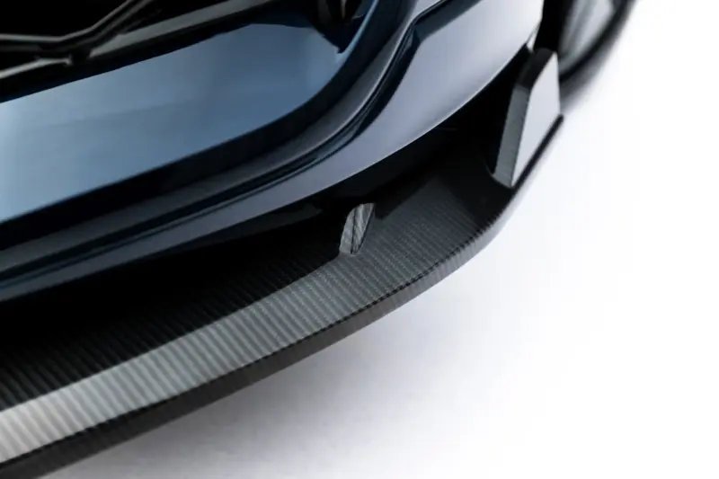 pol_po_Set-of-Prepreg-Carbon-Fiber-Splitters-Audi-RSQ8-Mk1-Facelift-23818_19webp - OPSHOLDERS Close-up of a glossy black car wheel with a carbon fiber rim and tire against a light background.