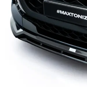 Close-up of a black car front with a hex grille and a carbon fiber lip, featuring the hashtag '#MAXTONIZED' on the bumper plate
