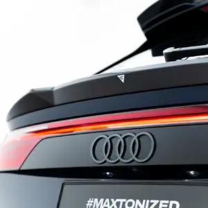 Rear view of a dark Audi SUV showing a carbon-fiber spoiler, red taillight strip, and the four-ring logo with the hashtag #MAXTONIZED on the tailgate.