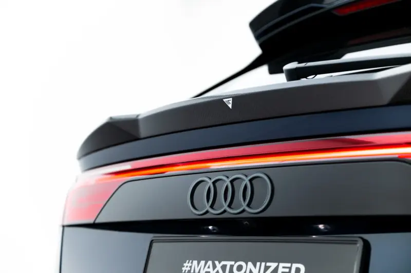 pol_po_Set-of-Prepreg-Carbon-Fiber-Splitters-Audi-RSQ8-Mk1-Facelift-23818_8webp - OPSHOLDERS Rear view of a dark Audi SUV showing a carbon-fiber spoiler, red taillight strip, and the four-ring logo with the hashtag #MAXTONIZED on the tailgate.
