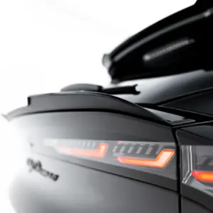 Close-up of a sleek black car with illuminated orange tail lights and design details along the trunk edge.