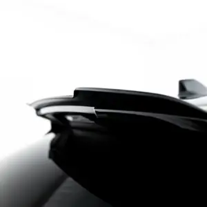 Close-up of a shiny black car surface with chrome trim against a white background.