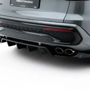 Close-up of the rear end of a silver SUV, showing the bumper, hexagonal rear trim, dual exhaust tips, and a dark license plate area with '#MAXTONIZED' text on it.