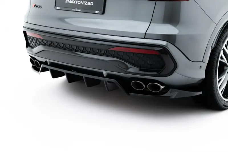 Close-up of the rear end of a silver SUV, showing the bumper, hexagonal rear trim, dual exhaust tips, and a dark license plate area with '#MAXTONIZED' text on it.