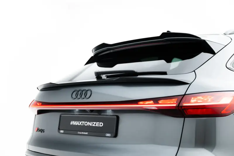 Rear view of a silver Audi with illuminated taillights, visible quattro badge, and a spoiler; the license plate area shows the text #MAXTONIZED.