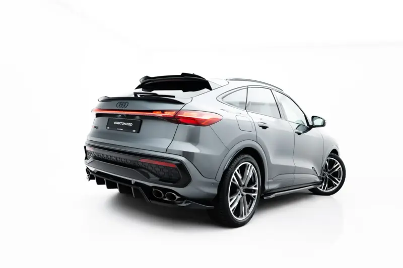 Rear three-quarter view of a grey Audi SUV with illuminated taillights; the glossy bumper and aftermarket spoiler are visible, and the license plate reads '#MAXTONIZED'.