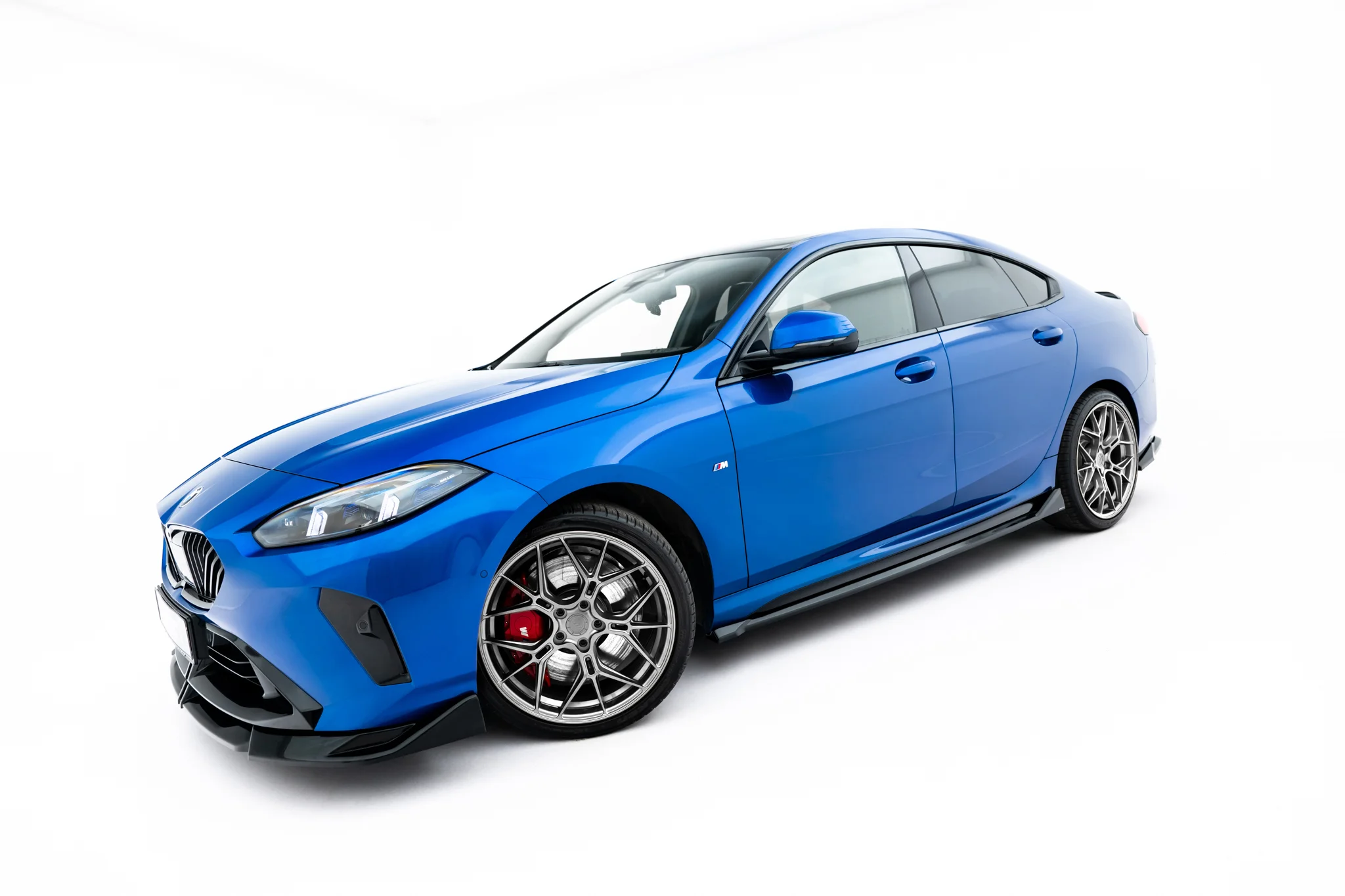 pol_po_Set-of-Splitters-BMW-2-M-Pack-Gran-Coupe-F74-23856_4webp - OPSHOLDERS Blue BMW M sports car photographed from a low front-left angle, showing its aggressive bumper and large alloy wheels.
