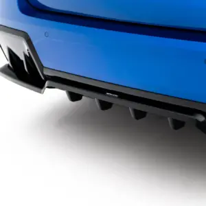 Close-up of a blue car bumper with a black lower lip and a small Maxton Design badge.