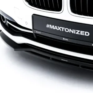 Close-up of the white BMW front end with a black license plate that reads “#MAXTONIZED.”