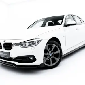 White BMW sedan photographed from a front-side angle in a bright studio setting with visible BMW emblem and alloy wheels