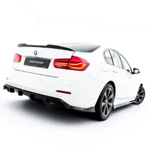 Rear three-quarter view of a white BMW sedan with a black spoiler and taillights, license plate reads '#MAXTONIZED'