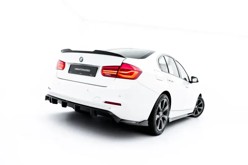 Rear three-quarter view of a white BMW sedan with a black spoiler and taillights, license plate reads '#MAXTONIZED'