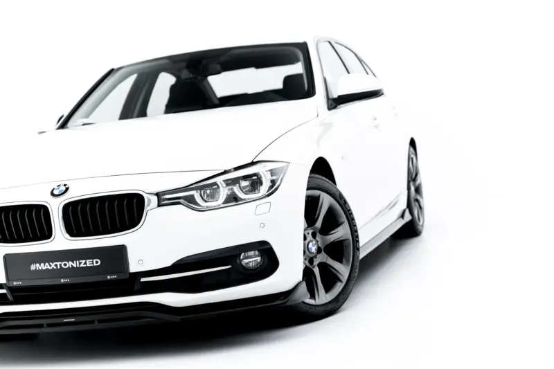 White BMW car shown from a low front-left angle, showcasing the grille, headlight, and alloy wheel with #MAXTONIZED license plate area.