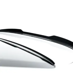 Close-up of a glossy black car side mirror against a white background on a white car body.