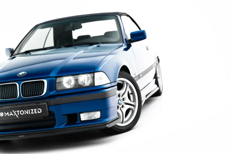 Blue BMW car prominently shown from the front-left, featuring the grille, headlight cluster, wheel, and a #MAXTONIZED license plate.