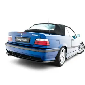 Rear three-quarter view of a blue BMW 320i convertible with a black soft top up, against a white background.
