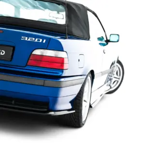 Blue BMW 320i convertible viewed from the rear-left, featuring a black soft top and '#MAXTONIZED' plate area from the back side.