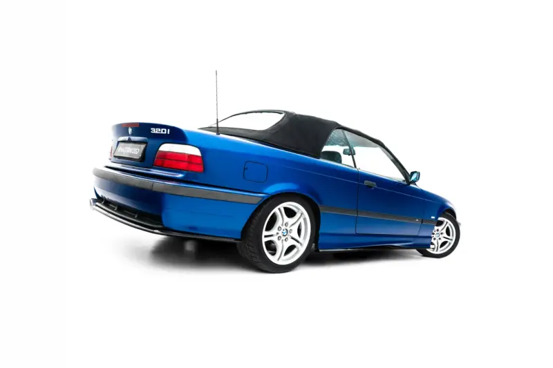 Blue BMW 320i convertible viewed from the rear-left, with a black soft top and alloy wheels, car on a white background