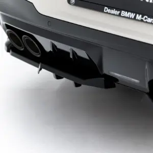 Close-up of the rear bumper of a dark BMW car, showing twin exhaust tips and a sporty diffuser.