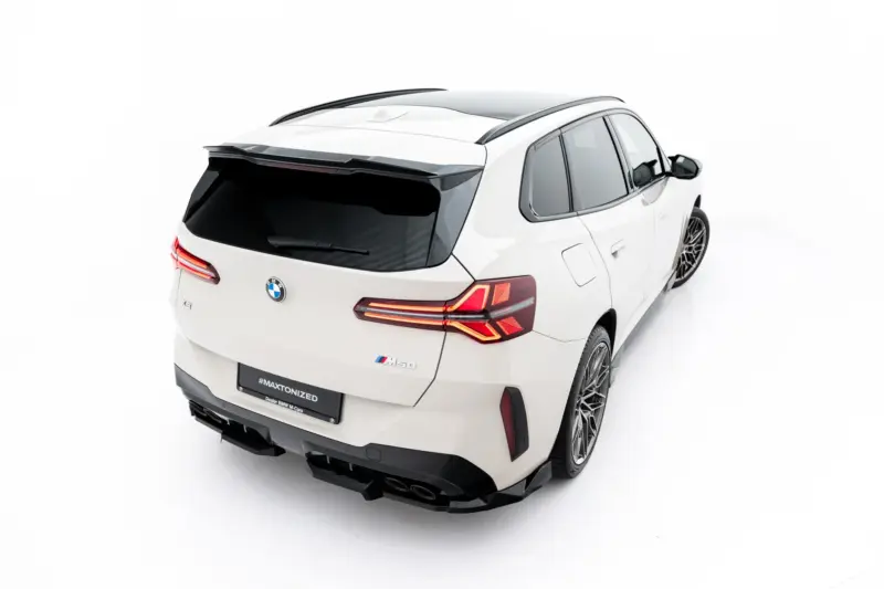 White BMW SUV photographed from rear-left, showing taillights, rear spoiler, roof rails, and alloy wheels; badge reads M50 and plate shows #MAXTRONIZED