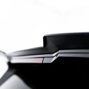 Close-up of the rear end of a sleek black car, showing the trunk lid and taillight edge. (informative)