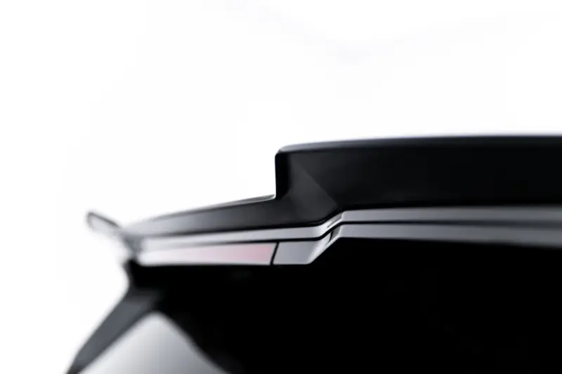 Close-up of the rear end of a sleek black car, showing the trunk lid and taillight edge. (informative)