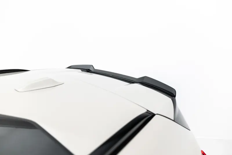Close-up of a white car roof showing black roof rails and a small spoiler against a light background.