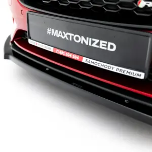 Close-up of a red car's front bumper showing a license plate with the hashtag '#MAXTONIZED' and a slogan strip reading 'DRIVE YOUR DREAM'.