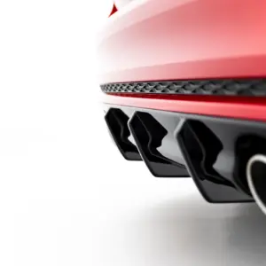 Close-up of a red car’s front section showing a black honeycomb vent and glossy panels.