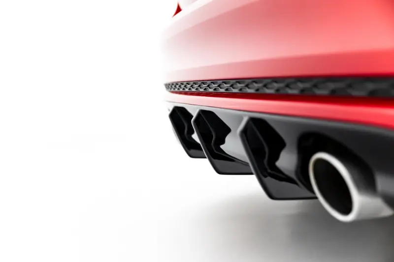 Close-up of a red car’s front section showing a black honeycomb vent and glossy panels.