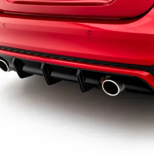Rear bumper of a red car showing dual exhaust pipes and a black diffuser area close up of the tail end