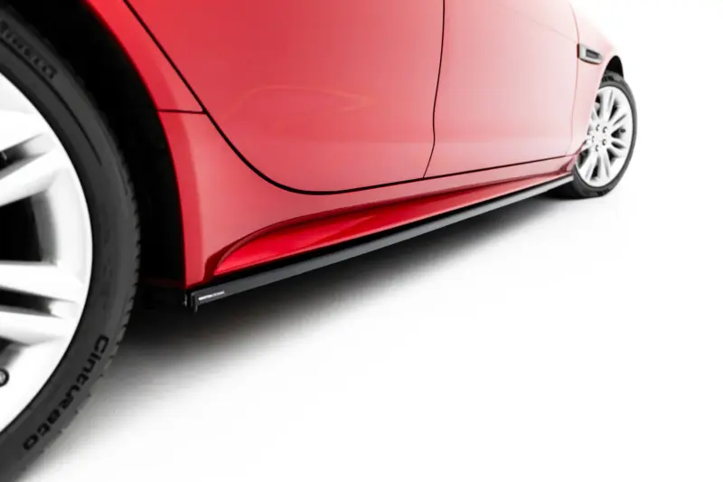 Close-up of a red car's side with a door seam and visible wheel, against a white background.
