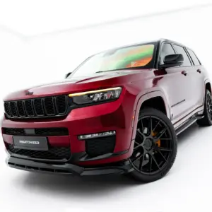 Three-quarter front view of a red Jeep Grand Cherokee in a white studio setting, showing the bold black grille and large alloy wheels, with #MAXTONIZED on the bumper.