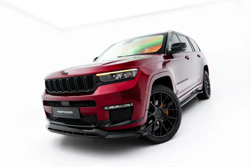 Three-quarter front view of a red Jeep Grand Cherokee in a white studio setting, showing the bold black grille and large alloy wheels, with #MAXTONIZED on the bumper.