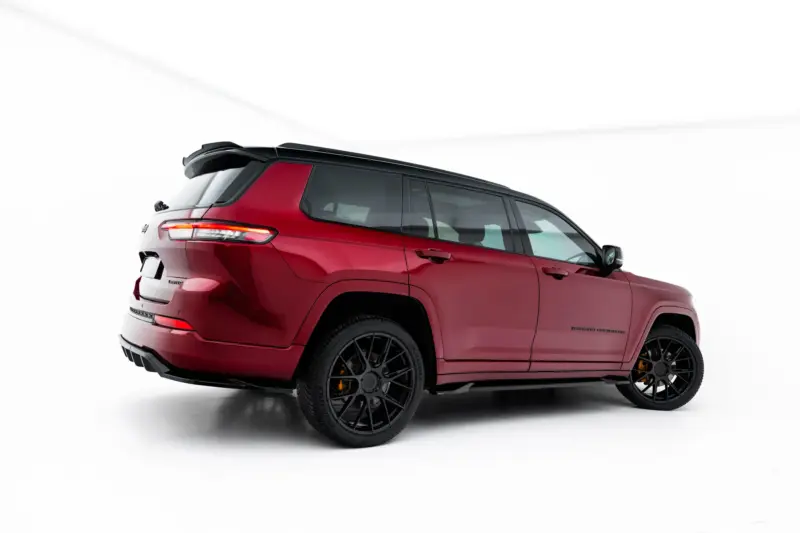 Red SUV shown from a rear three-quarter angle with a black spoiler, dark windows, and large black alloy wheels against a white studio backdrop.