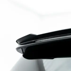 Close-up of a white car roof edge featuring a black glossy spoiler with a slim chrome accent.