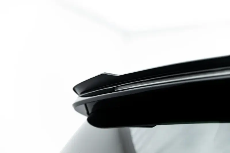 Close-up of a white car roof edge featuring a black glossy spoiler with a slim chrome accent.
