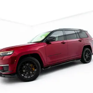 Front-left and side view of a red Jeep Grand Cherokee in a bright white studio setting.