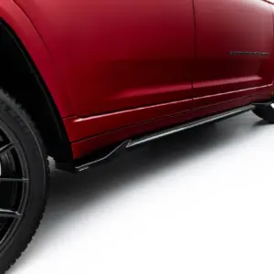 Close-up side view of a red Jeep Grand Cherokee, showing the front wheel, lower body line, and side step along the rocker.