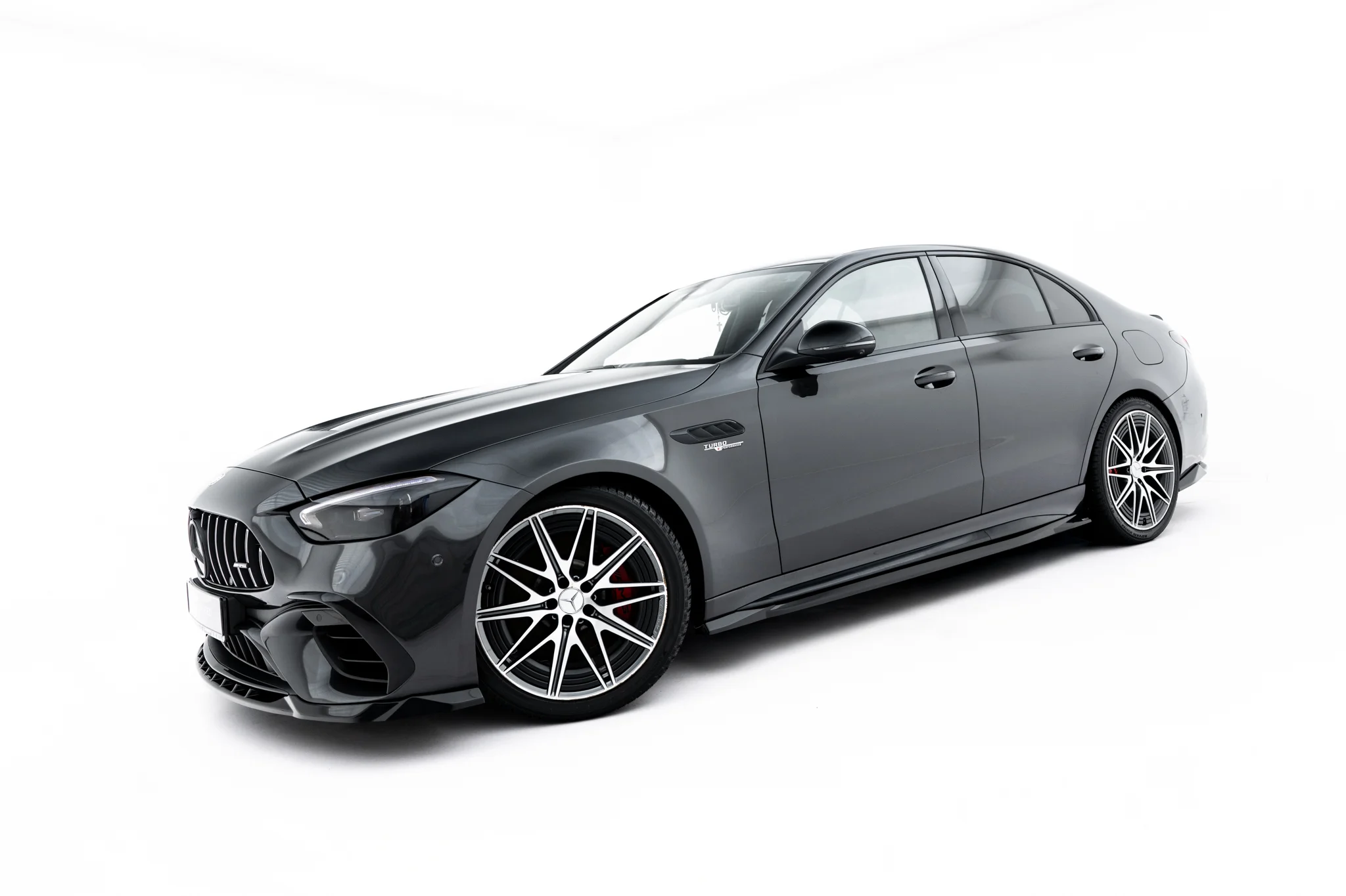 pol_po_Set-of-Splitters-Mercedes-AMG-C63-Sedan-Estate-W206-S206-23828_4webp - OPSHOLDERS Gray luxury sedan viewed from the front-left, featuring a prominent grille and large multi-spoke wheels on a white background.